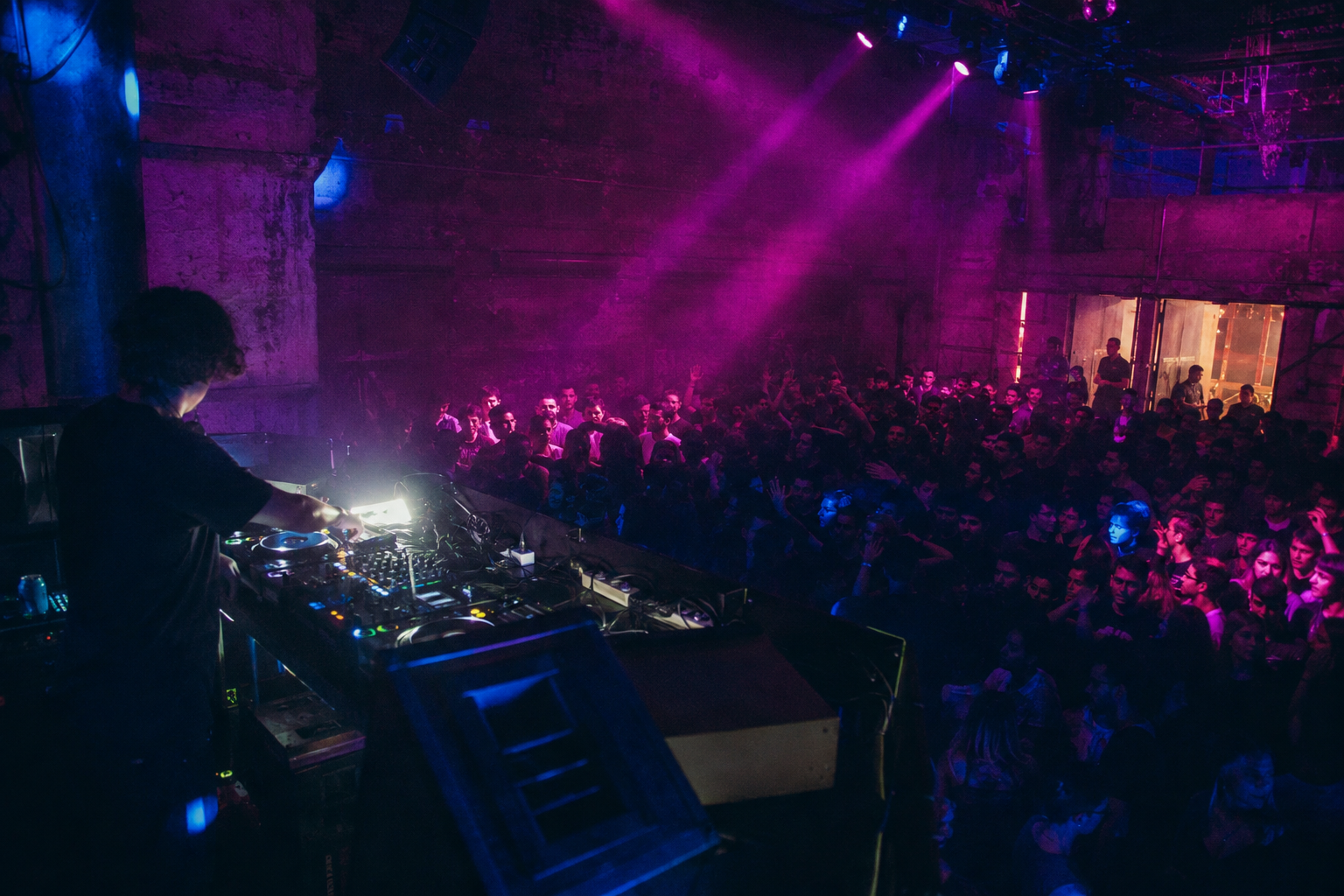 DJ performing to a crowd inside a dark club